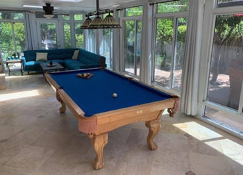 Close-up of a cue ball slowly drifting on an uneven pool table in a Sacramento home